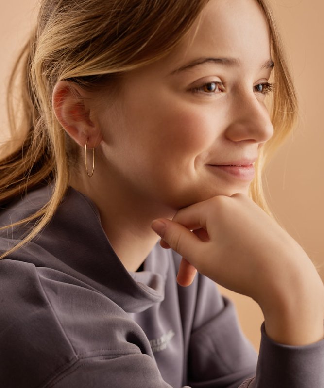 Tienermeisje met oorbellen Blomdahl titanium goudkleurige oorringen groot 30 mm. - Staartjes en Strikjes