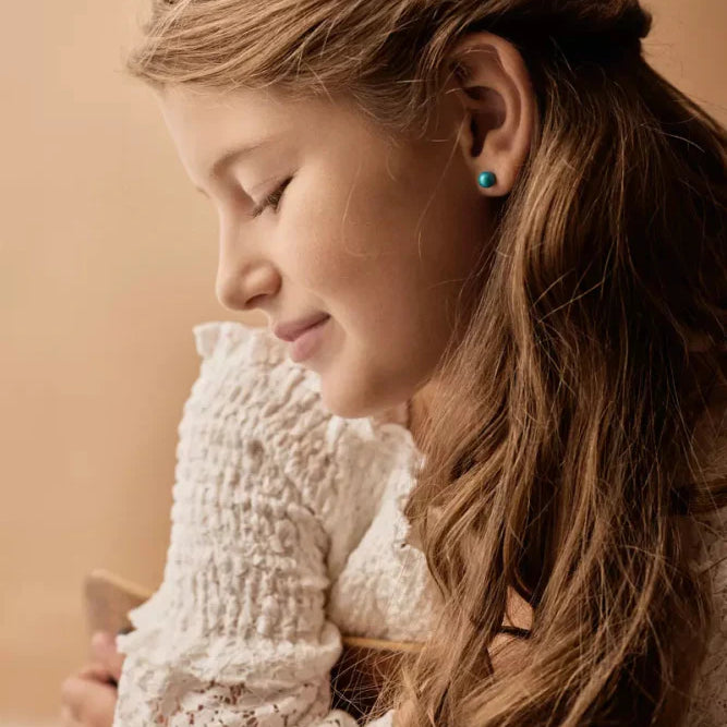 Een meisje met een setje hypoallergene oorbellen van Blomdahl in.