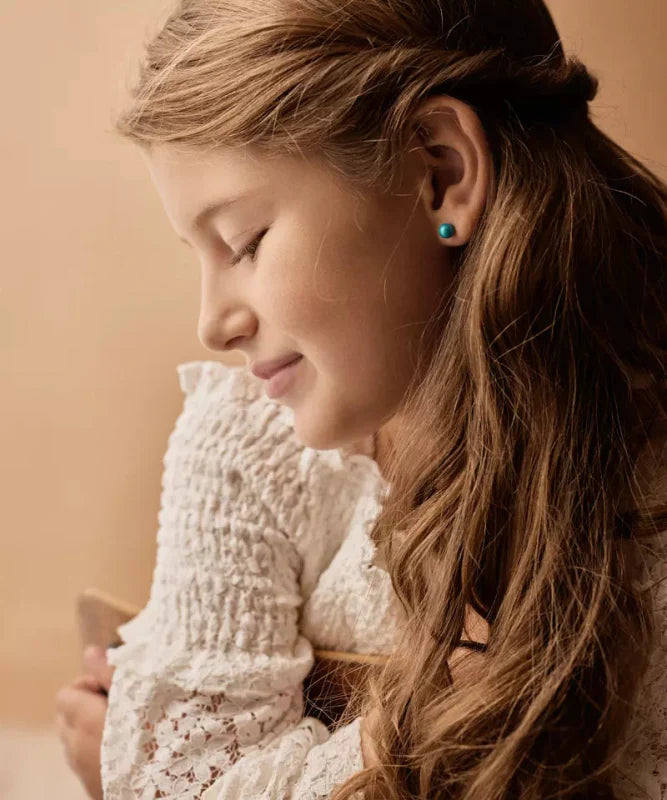 Een meisje met een setje hypoallergene oorbellen van Blomdahl in.